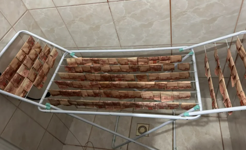 Dinheiro no varal: polícia encontra pilhas de notas secando e em mala